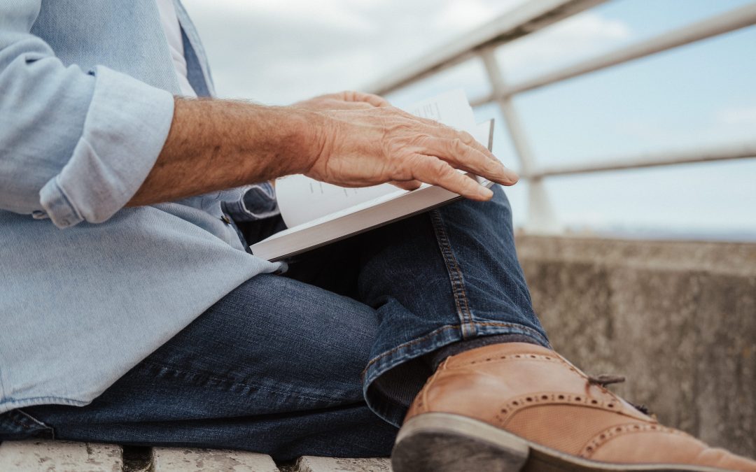 Close up of a pensioner reading a book by the coast.