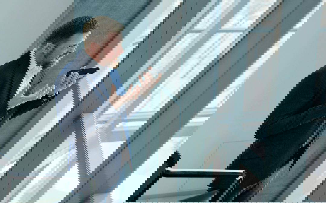 Narcissistic man in a suit holding a phone speaking to someone and seems extremely angry