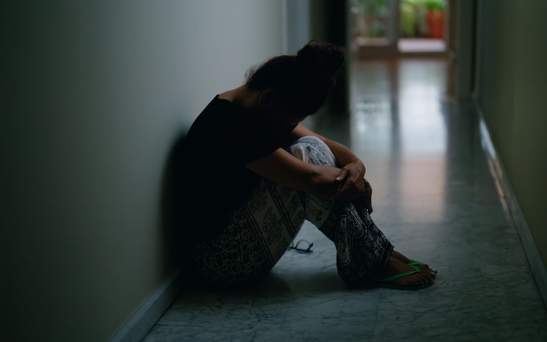 Woman suffering from domestic abuse sitting on the floor feeling failed by the family justice system