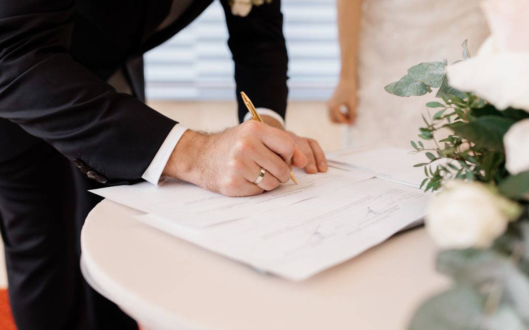 Couple signing official marriage documents and may consider signing a prenup to protect their future financial position